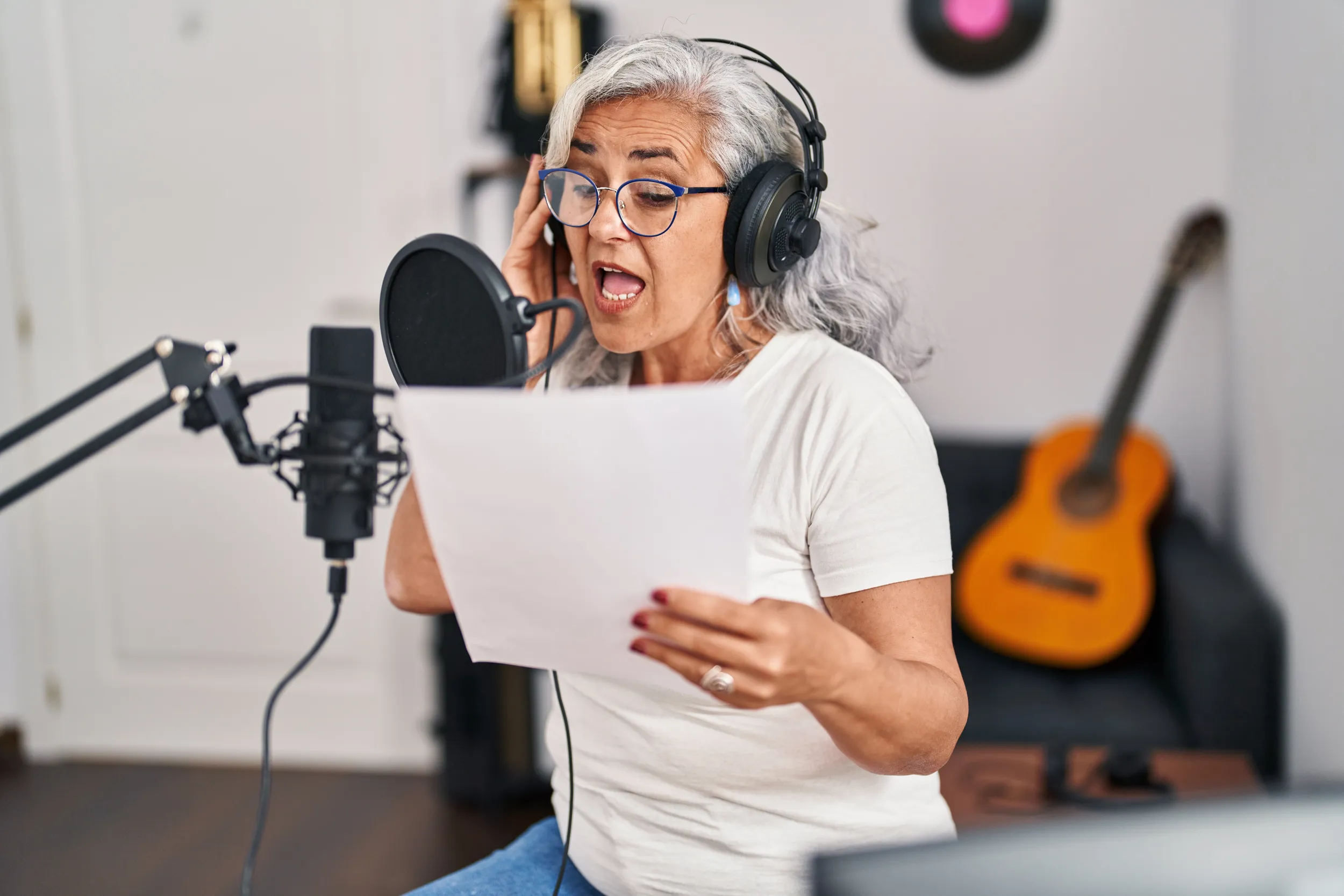 Una donna dai capelli grigi che canta davanti al microfono