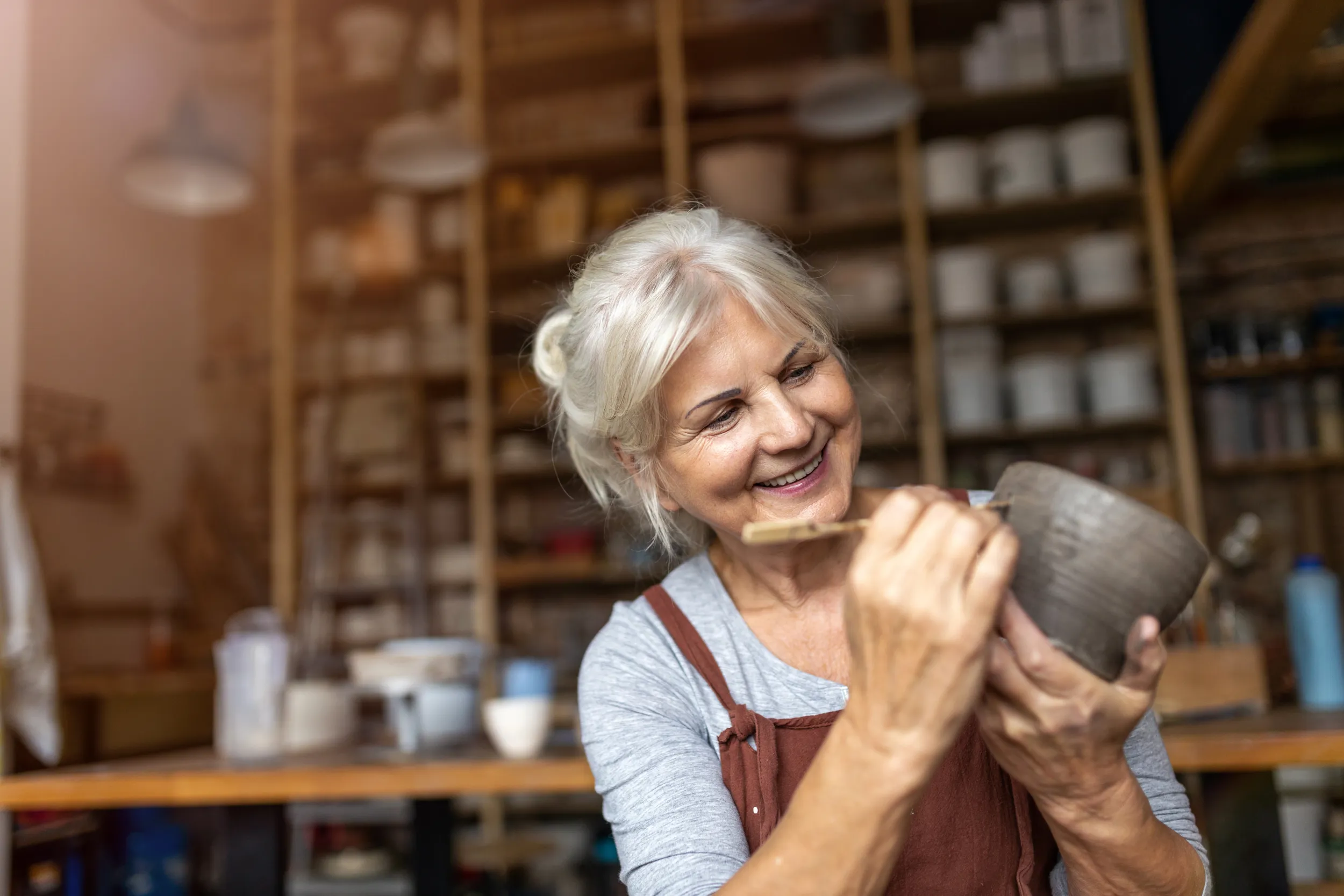 Donna dai capelli grigi intenta a lavorare al tornio e a modellare
